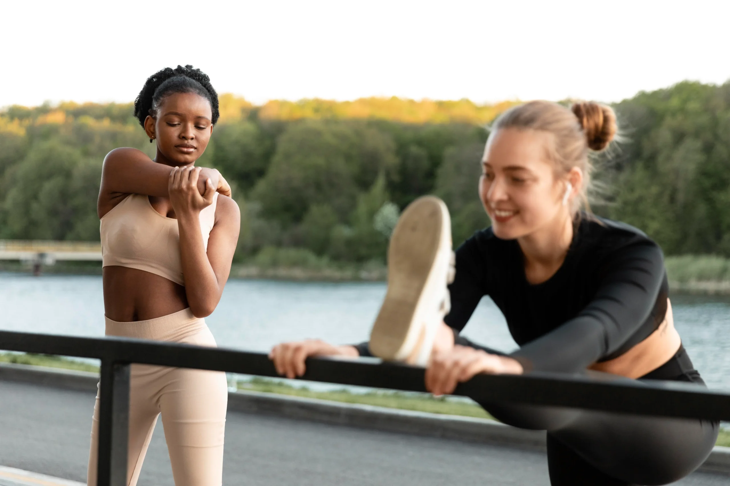 Two women stretching outdoors, representing the habit of exercise for health success.