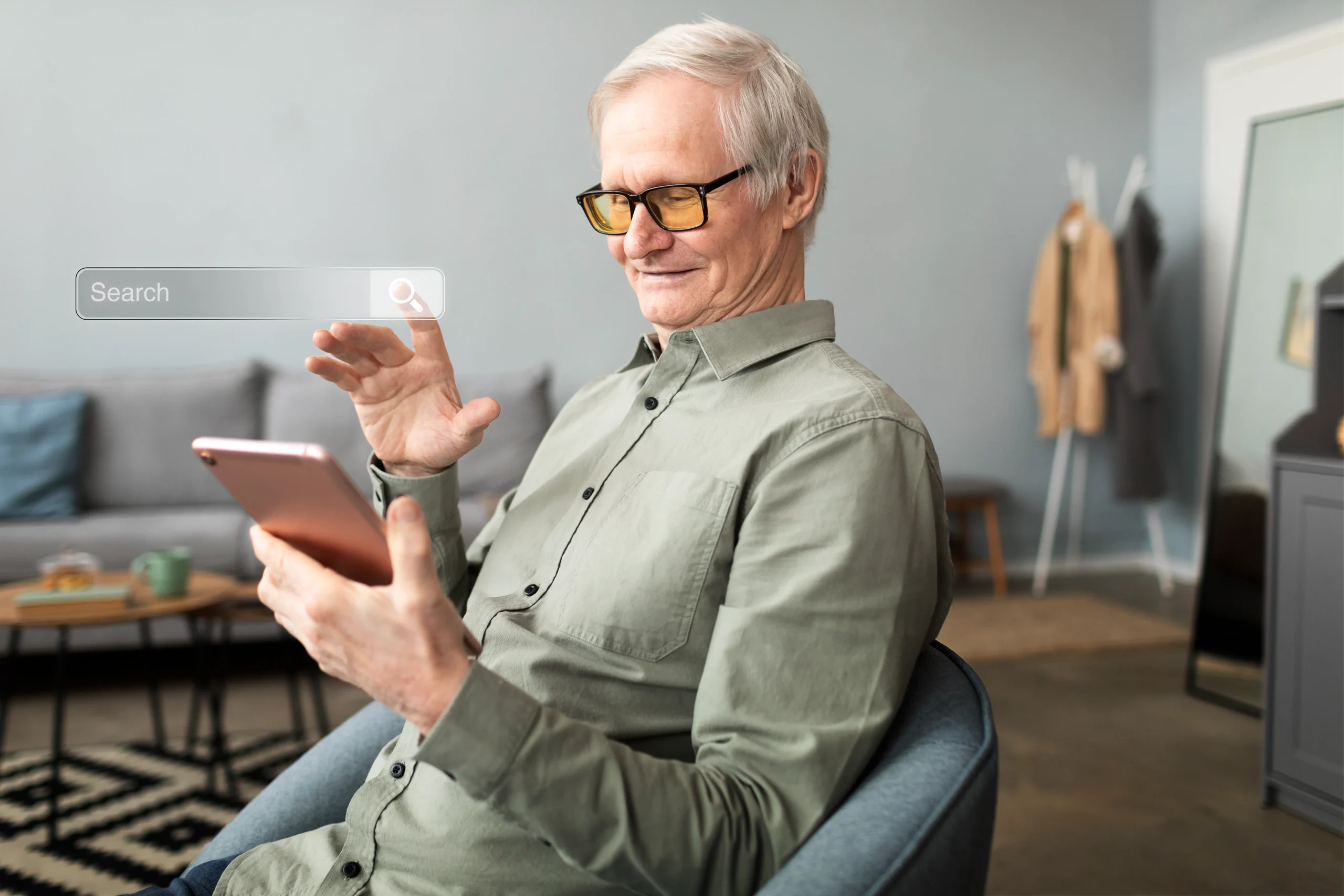 A smiling senior man with glasses interacting with a tablet, with a holographic search bar visible, representing technology aiding independent living. The text overlay reads: "Embracing Technology for Independent Living. Another significant innovation is the application of information and communication technologies to facilitate aging in place. Robo-advisors, for instance, provide personalized financial planning and management services tailored to older adults. Meanwhile, smart home technologies are being utilized to monitor daily activities and ensure safety, empowering seniors to maintain their independence for longer and reducing reliance on institutional care."